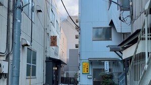 Una calle urbana estrecha con edificios a ambos lados, una entrada visible a un edificio con un letrero y una flecha roja apuntando hacia adelante.