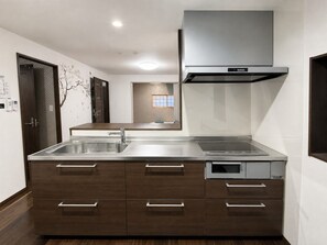 A modern kitchen with a stainless steel sink, wooden cabinets, and a built-in oven. - 15 Minutes from Haneda Airport! Traditional Japanese Inn "FUKA" (Ota)