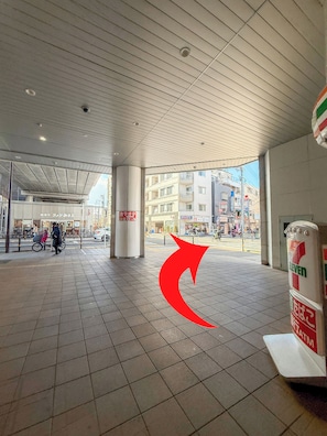 A spacious indoor area with tiled flooring, a high ceiling, and a view of the street outside.