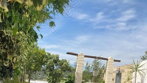 A garden pathway leading to a stone entrance with a wooden archway. - Villa Sara of Apulia - Triple (Masseria Gaudella)