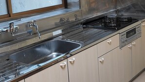 Une cuisine équipée d’une cuisinière en acier inoxydable, d’un évier et de meubles de rangement de couleur claire.