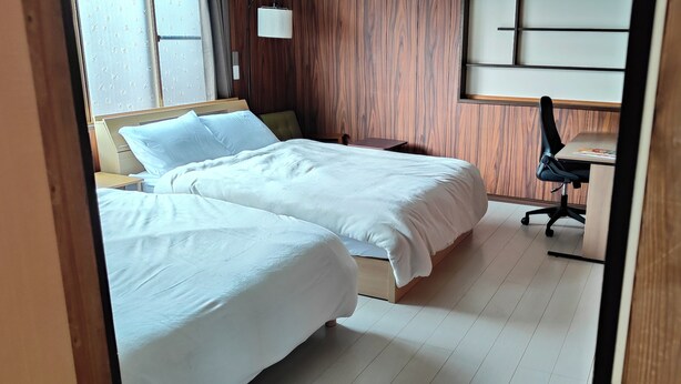 Une chambre d’hôtel avec deux lits, un bureau et une chaise.