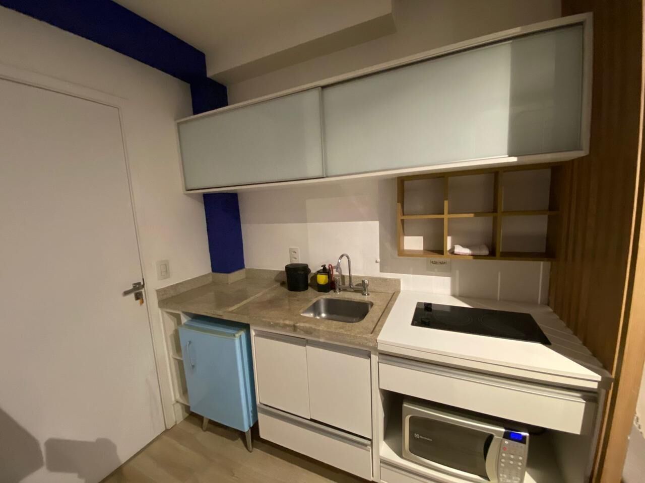Een kleine keuken met een spoelbak, fornuis en een kleine koelkast.