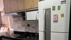 Une cuisine moderne dotée d’un réfrigérateur en acier inoxydable, d’un four encastré et d’un plan de travail noir.