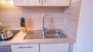 Une cuisine moderne avec un évier en acier inoxydable, des armoires en bois et une casserole sur la cuisinière.