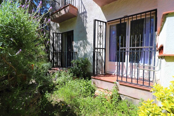 A building with a balcony, a window with metal bars, and a door.