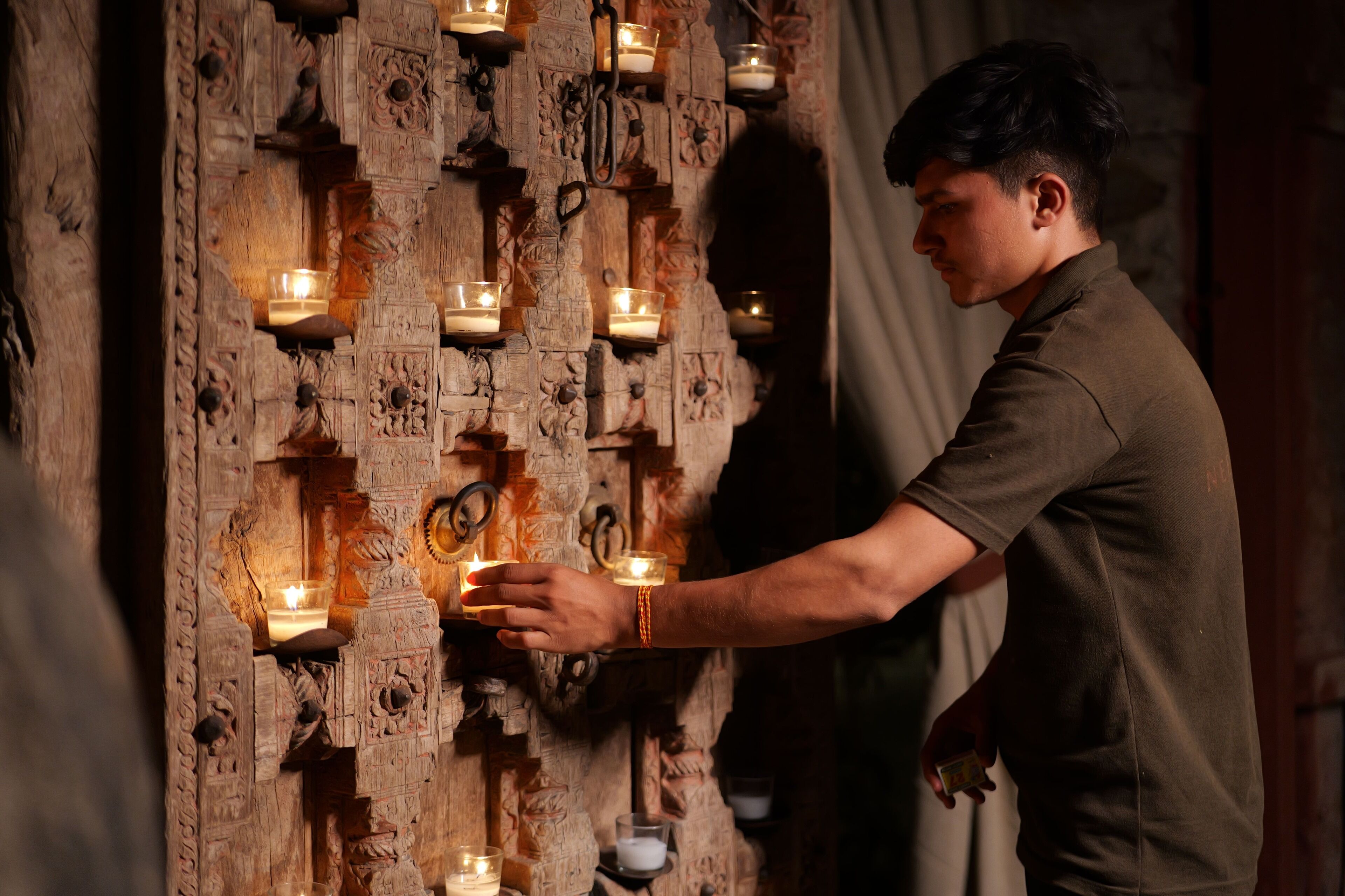 Una persona encendiendo velas en una habitación con elaborados grabados de madera.