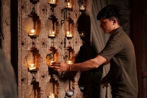 Una persona encendiendo velas en una habitación con elaborados grabados de madera.