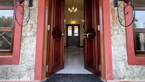 A hotel entrance with a stone facade, wooden doors, and a chandelier. - Neem Sarai Sariska (Rajgarh)