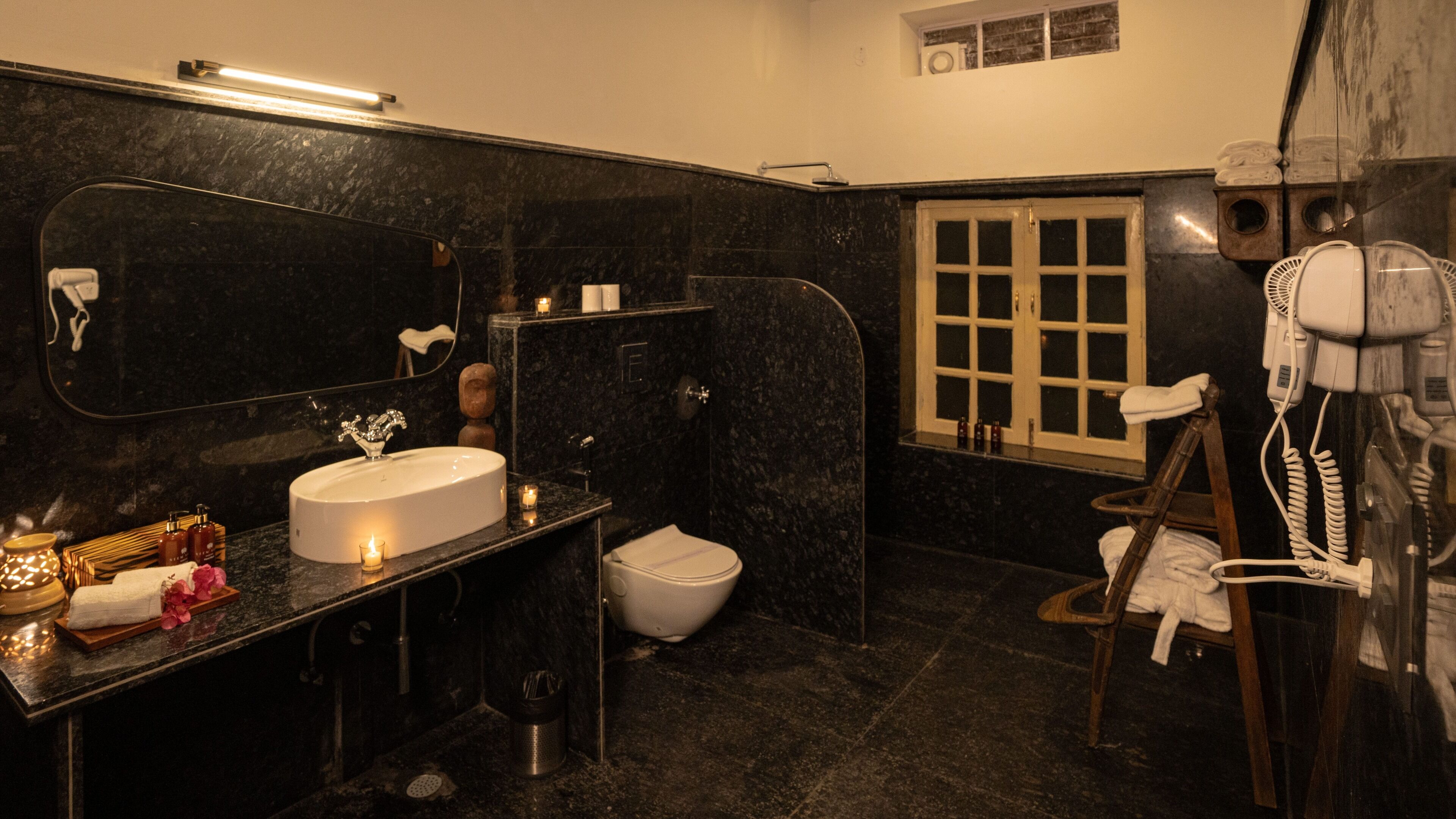 A bathroom with a large mirror, a sink, a toilet, and a hairdryer.