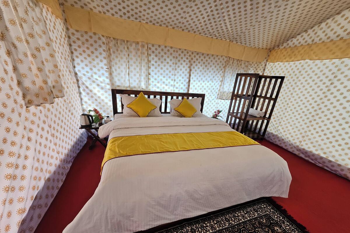 Una habitación con cama, cortinas, cabecero de madera y alfombra estampada.