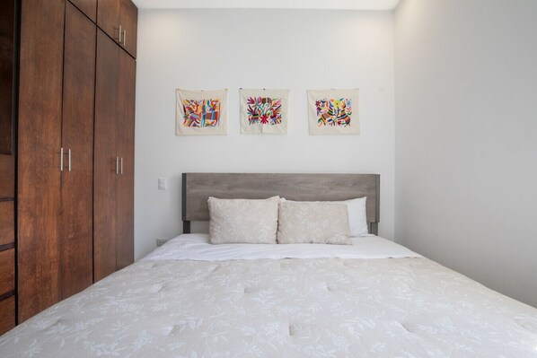 Ein Schlafzimmer mit Bett, Holzschrank und drei Wandbildern.