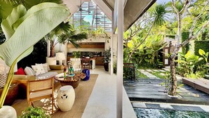 A modern living area with a kitchen, dining space, and a water feature. - Kawung Villa Canggu (Canggu)