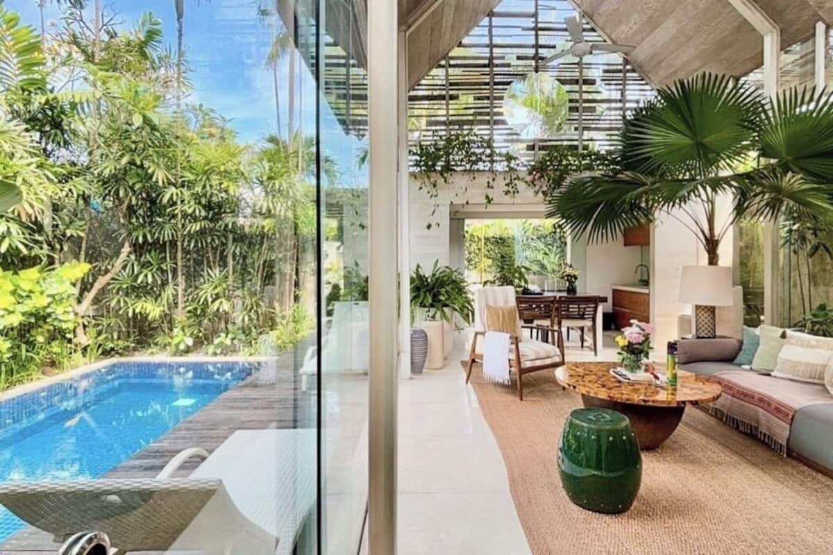 Un espace intérieur moderne doté d’une piscine, de sièges confortables et d’une végétation luxuriante.