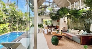 A modern indoor space with a pool, comfortable seating, and abundant greenery. - Kawung Villa Canggu (Canggu)