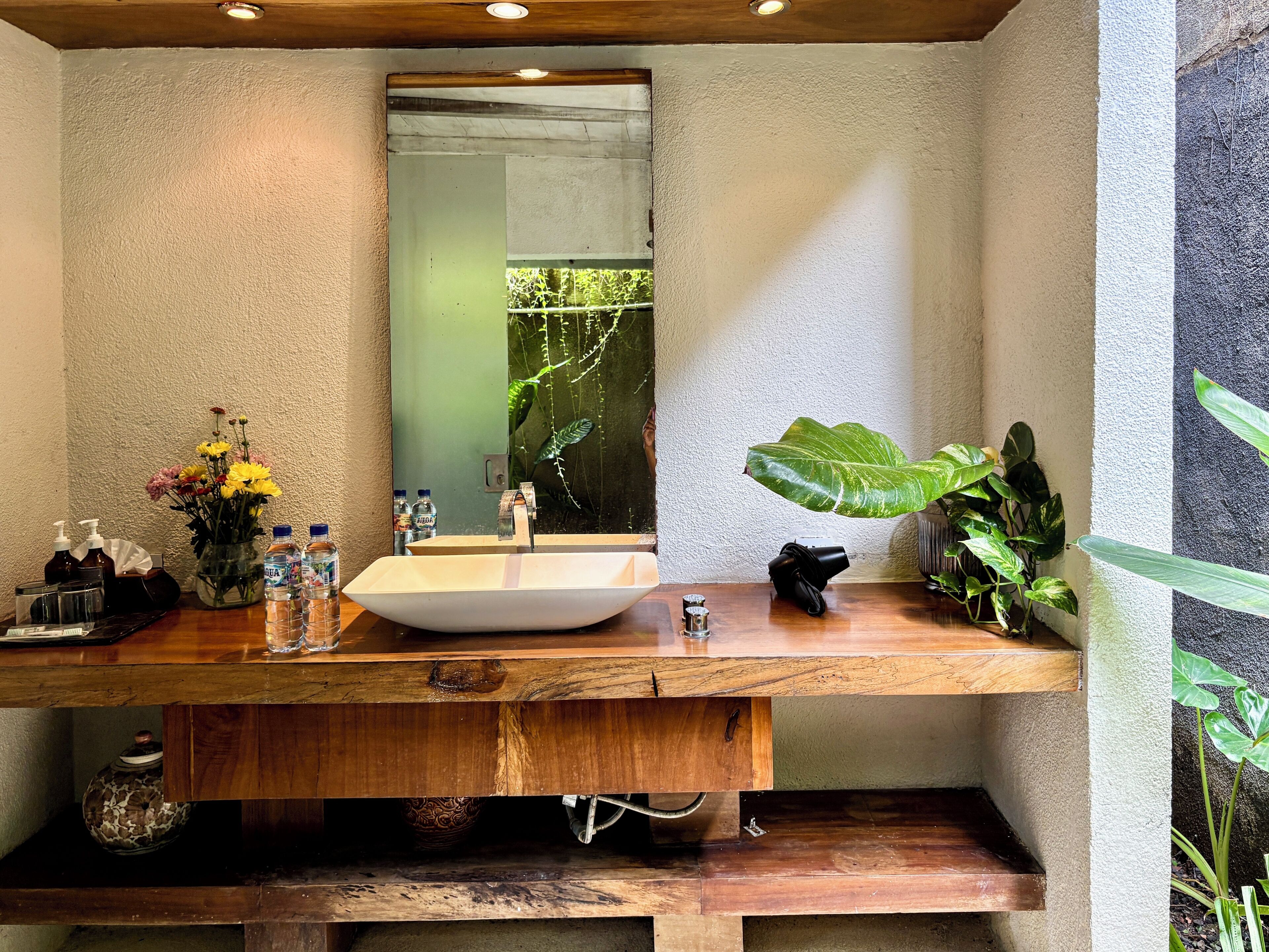 Ein Badezimmer mit einem Holzbadschrank, einem großen Spiegel und einem Waschbecken.