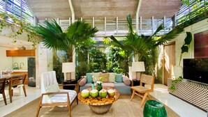 A modern living room with a sofa, chairs, a coffee table, and a TV. - Kawung Villa Canggu (Canggu)