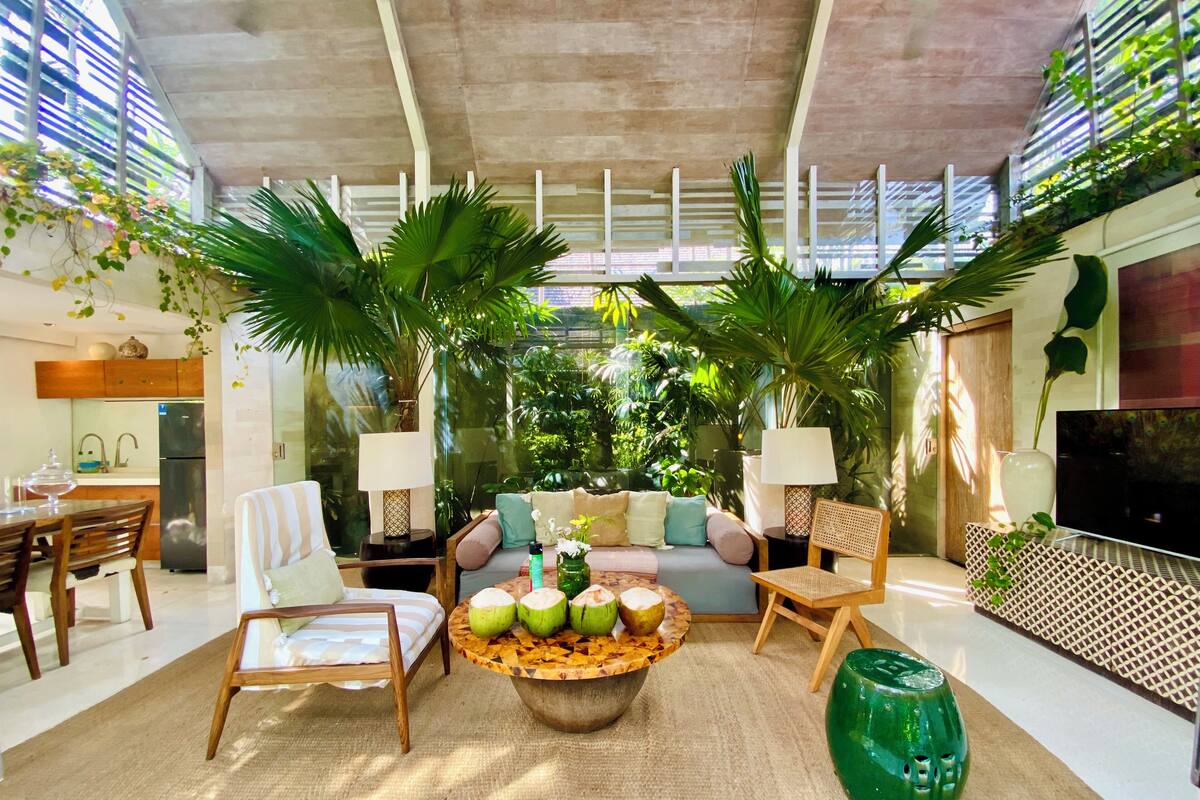 Un salon moderne avec un canapé, des fauteuils, une table basse et un téléviseur.