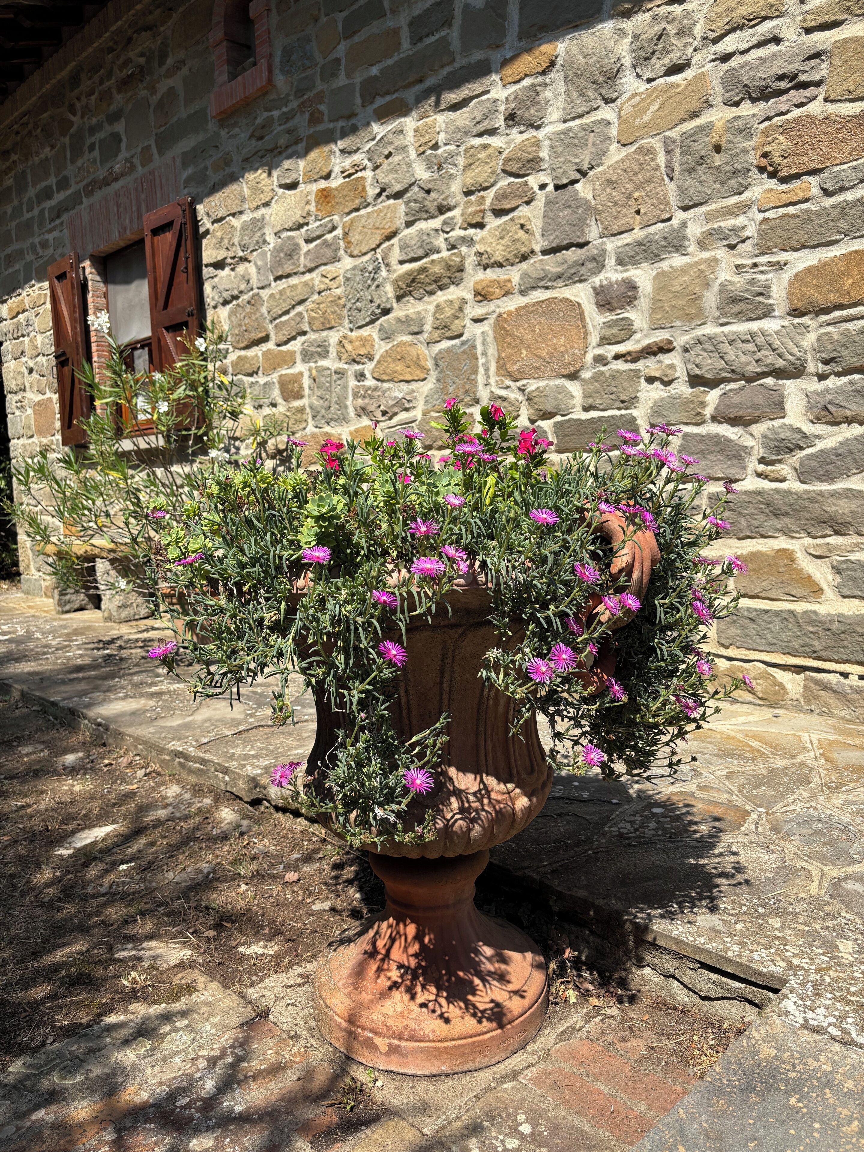 A stone building with a large flower pot in front.
