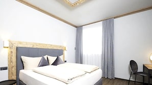 A modern hotel room with a large bed, a wooden headboard, a desk with a chair, and a large window with curtains. - Holiday Home for 3 People in Brixlegg (Brixlegg)