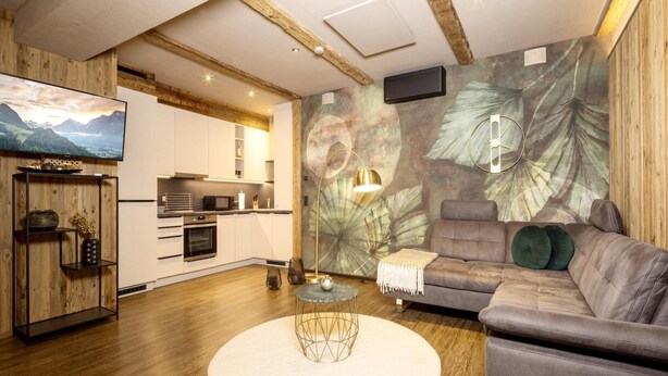 A modern living room with a grey sofa, a round coffee table, and a TV on the wall. - Holiday Home for 3 People in Brixlegg (Brixlegg)
