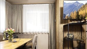 A dining area with a wooden table, chairs, and a vase of flowers. - Holiday Home for 3 People in Brixlegg (Brixlegg)