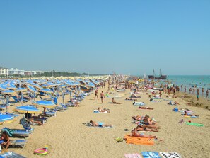 Ein überfüllter Strand mit vielen Sonnenschirmen und Liegestühlen.