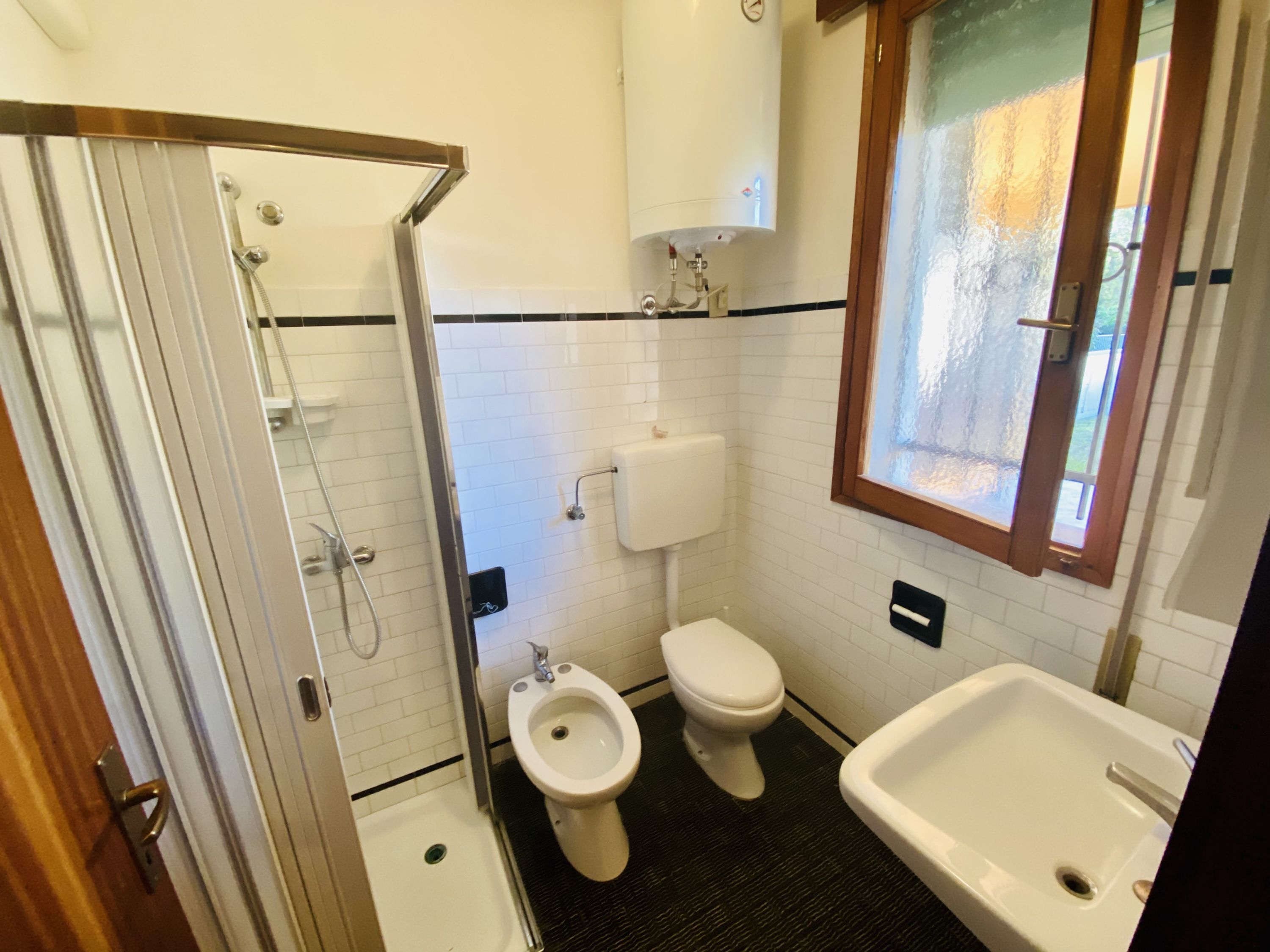 Un baño pequeño con ducha, inodoro, bidé y lavamanos.