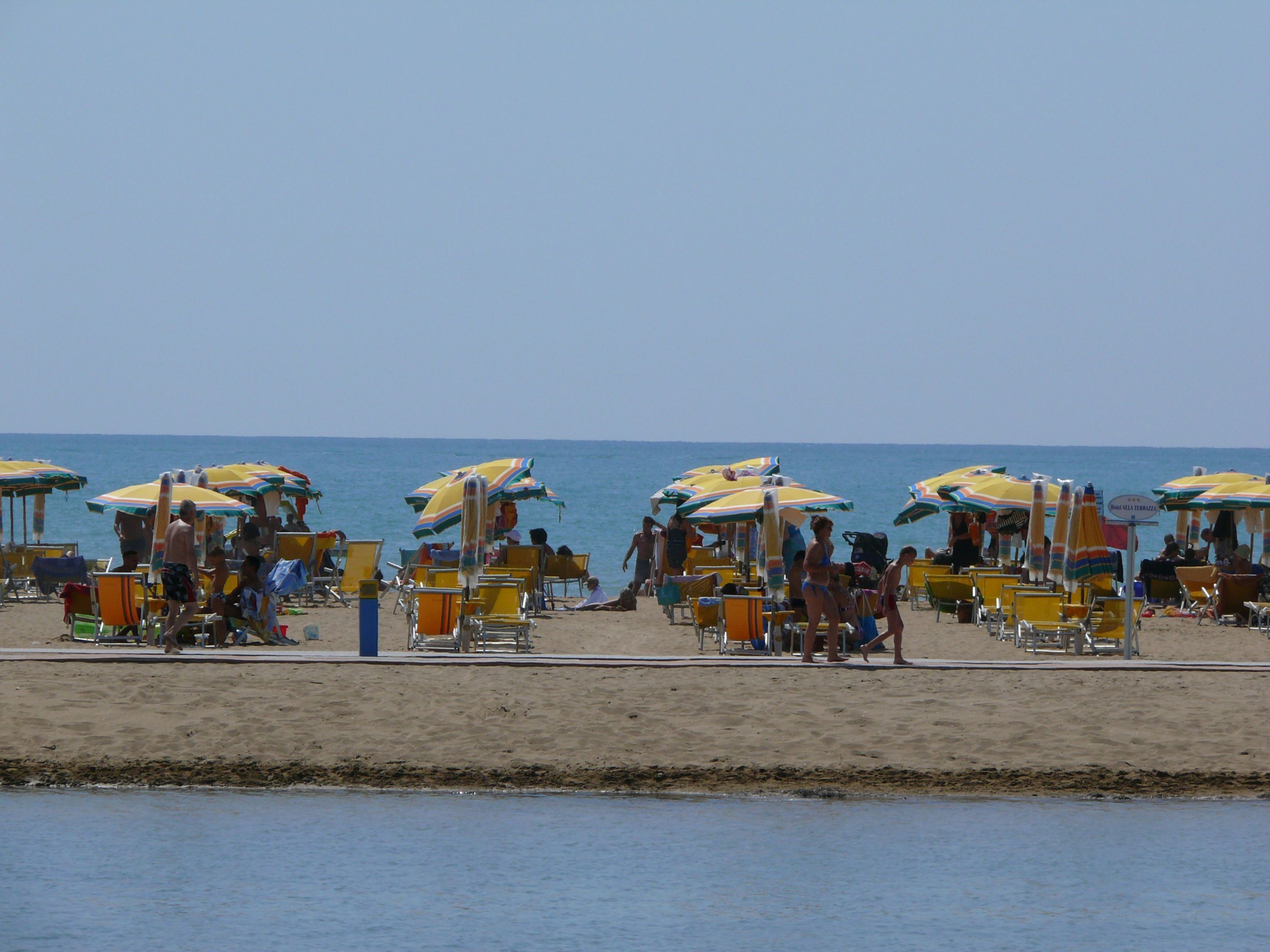 Een strand met rijen parasols en ligbedden.