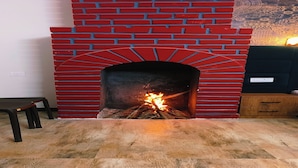 Une cheminée avec un décor en briques rouges et un feu qui crépite à l’intérieur.