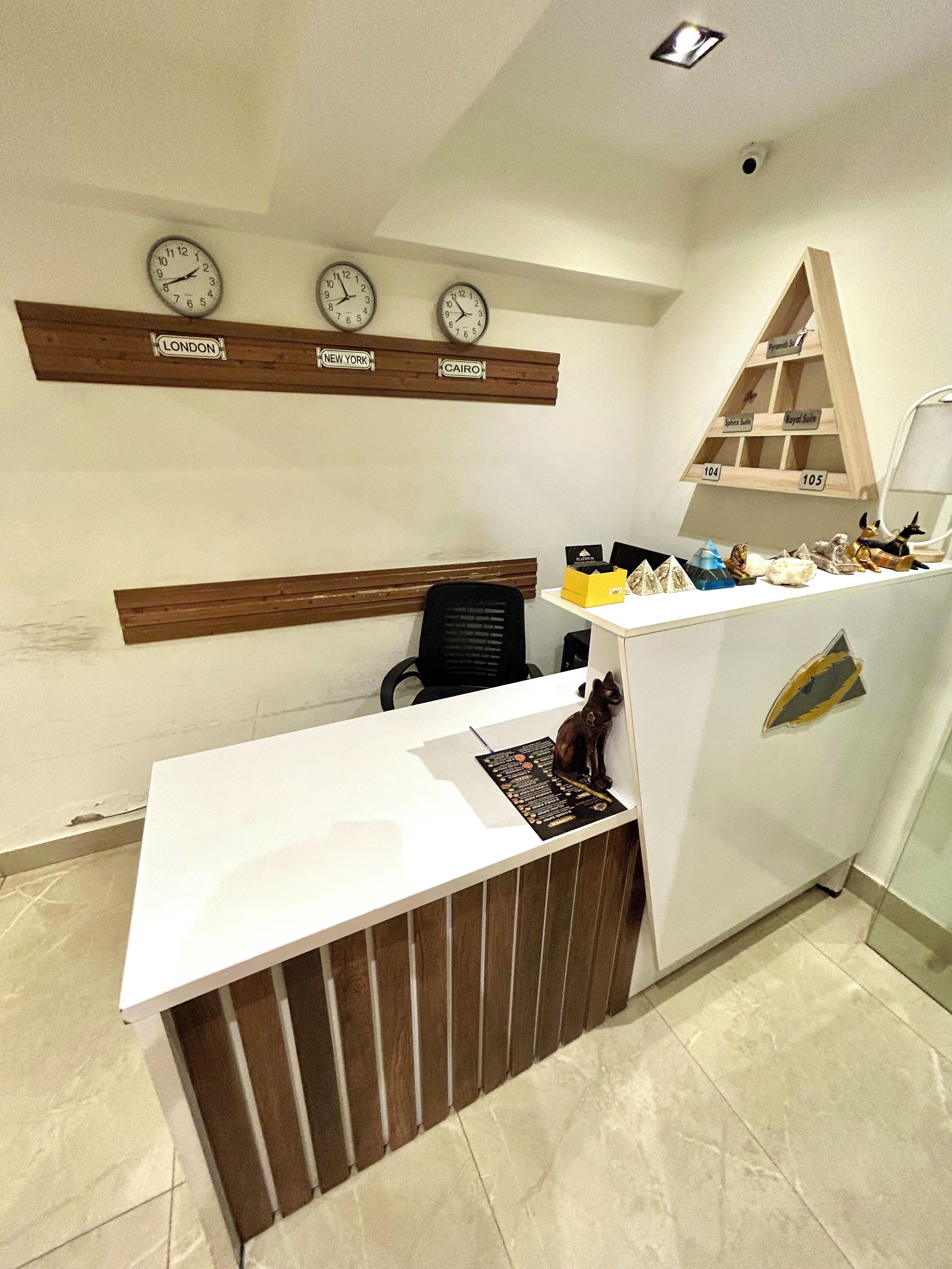 A reception desk with a wooden panel, a black office chair, and a wall clock displaying the time.