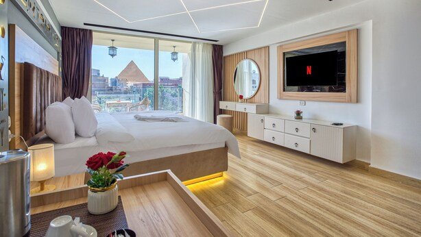 Una camera d'albergo moderna con un letto grande, una TV a parete e vista sulla città.