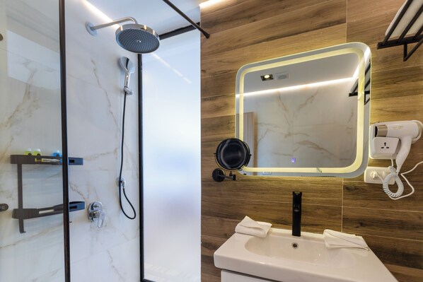 A bathroom with a shower, a sink, a mirror, and a hairdryer.