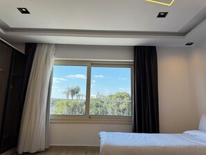 Une chambre avec une grande fenêtre, un lit et une armoire.