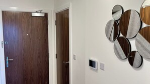 Un couloir avec deux portes en bois, un luminaire fixé au mur et un ensemble de miroirs décoratifs.