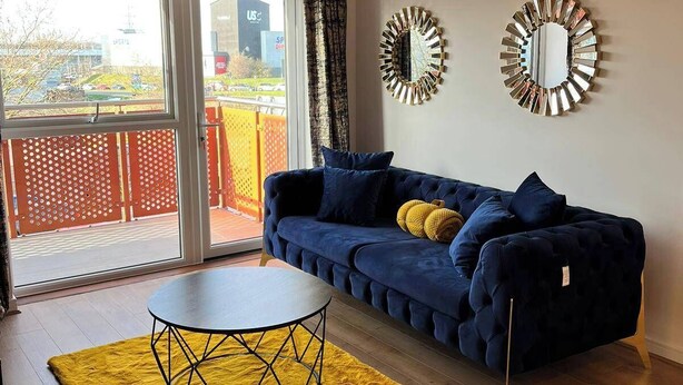 Un salon moderne avec un canapé bleu, un tapis jaune et une table ronde.
