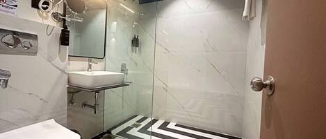Un baño moderno con cabina de ducha de vidrio, un lavamanos blanco y un suelo con estampado blanco y negro.
