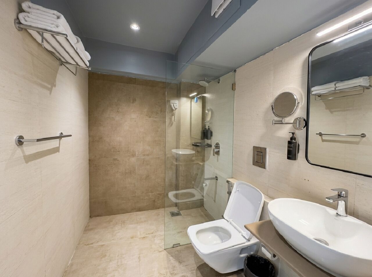 A modern bathroom with a glass-enclosed shower, a toilet, and a sink.