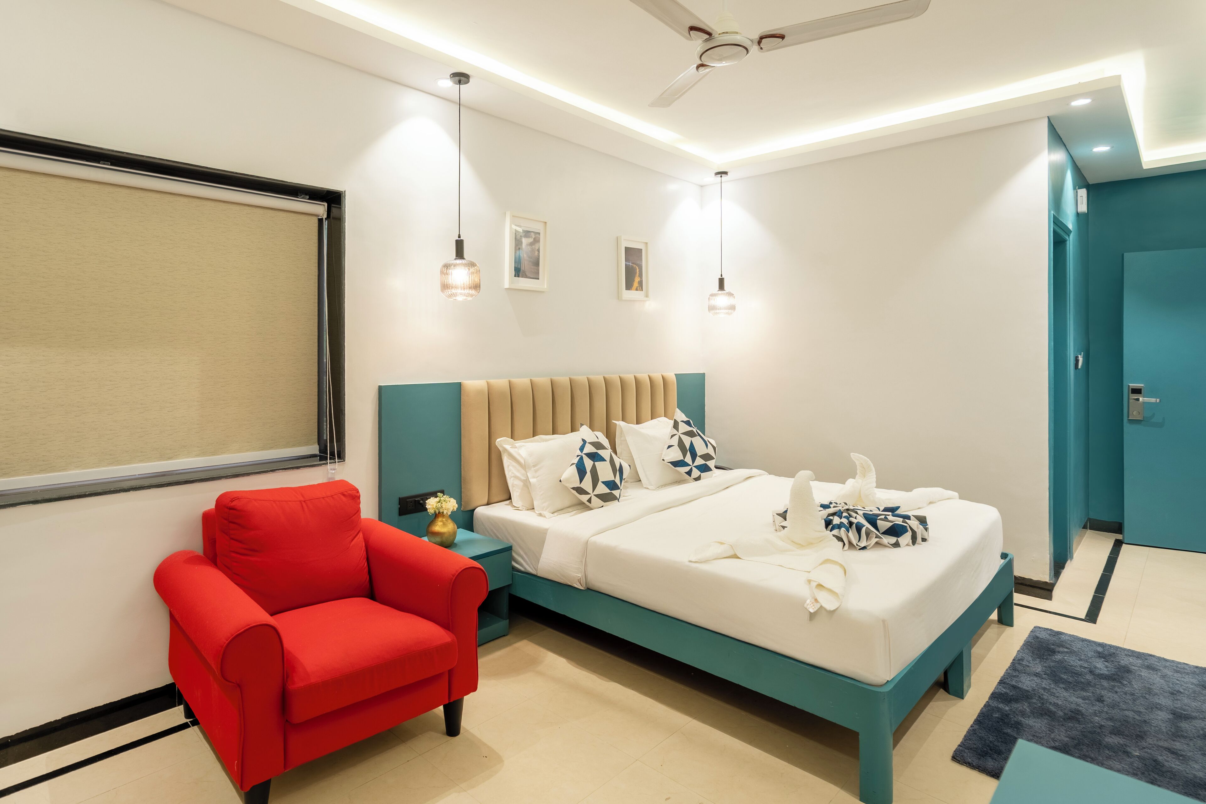 A modern bedroom with a bed, a red chair, and a ceiling fan.