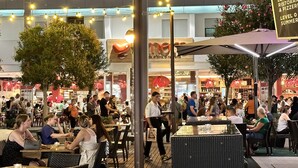 Un espace extérieur aménagé pour les repas, avec des guirlandes lumineuses, des tables et des chaises.