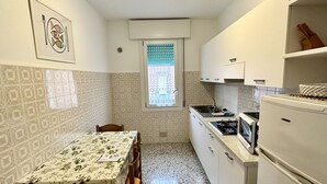 Une cuisine de taille réduite comprenant une table à manger, des chaises, une cuisinière et un réfrigérateur.