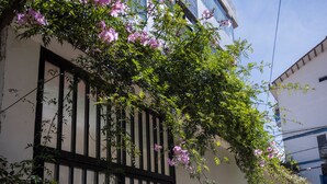 Un bâtiment doté d’une entrée fermée par un portail, un ciel dégagé et un trottoir.