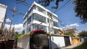 Un bâtiment moderne doté d’une entrée sécurisée par un portail, de grandes fenêtres et surplombant un ciel dégagé.