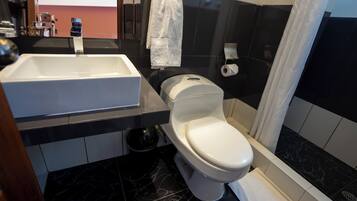 A modern bathroom with a white sink, black marble flooring, a white toilet, and a shower curtain.