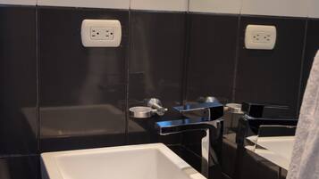 Un baño moderno con un lavamanos blanco, paredes con azulejos blanco y negro y una encimera negra.