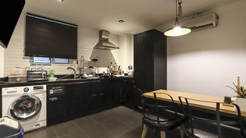 Uma cozinha moderna com máquina de lavar, uma área de refeições com mesa e cadeiras, e um arm ário preto.