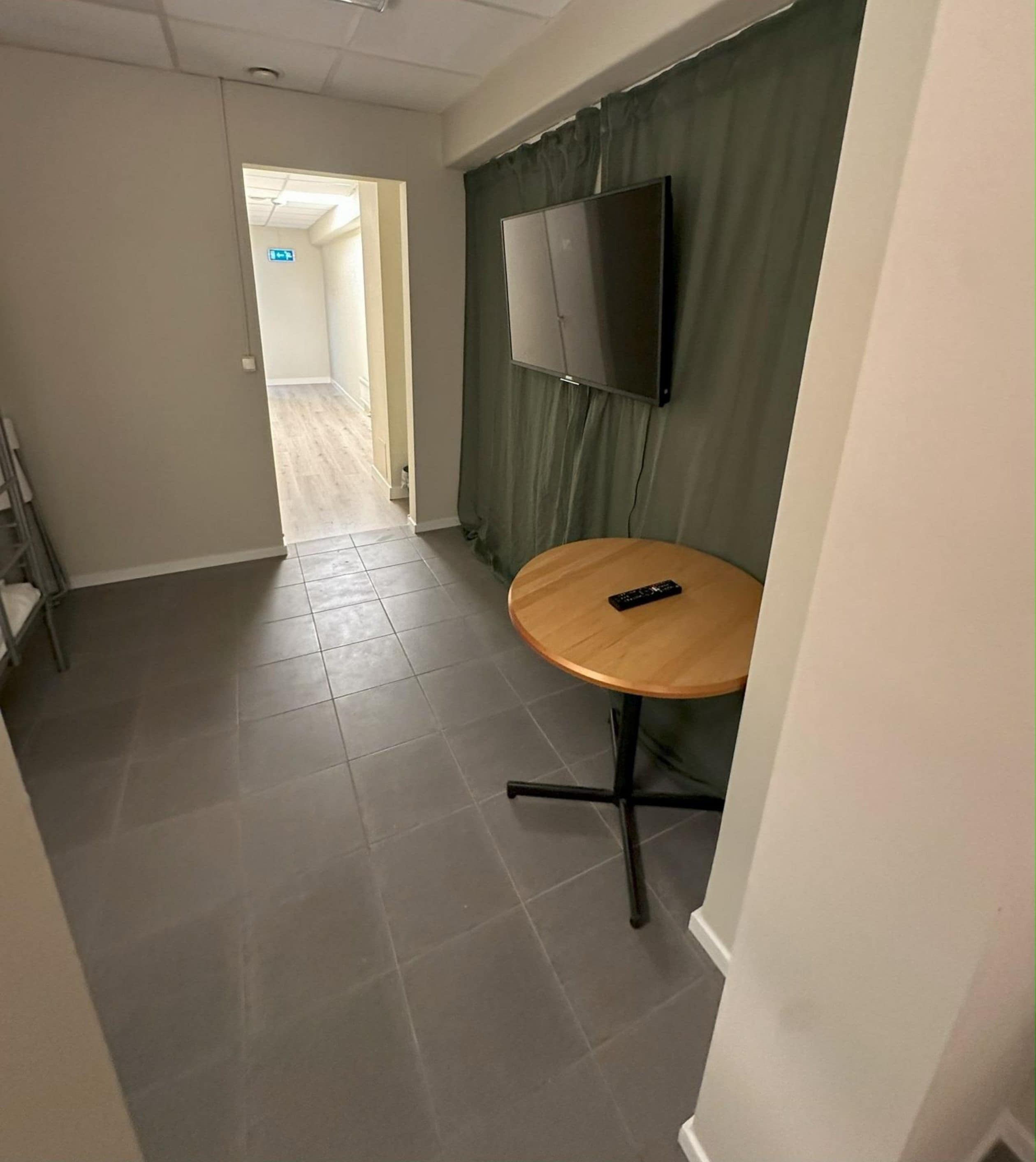 A 6-bed economy room with a shared bathroom, no window, and a TV mounted on the wall.