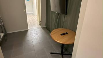A 6-bed economy room with a shared bathroom, no window, and a TV mounted on the wall.