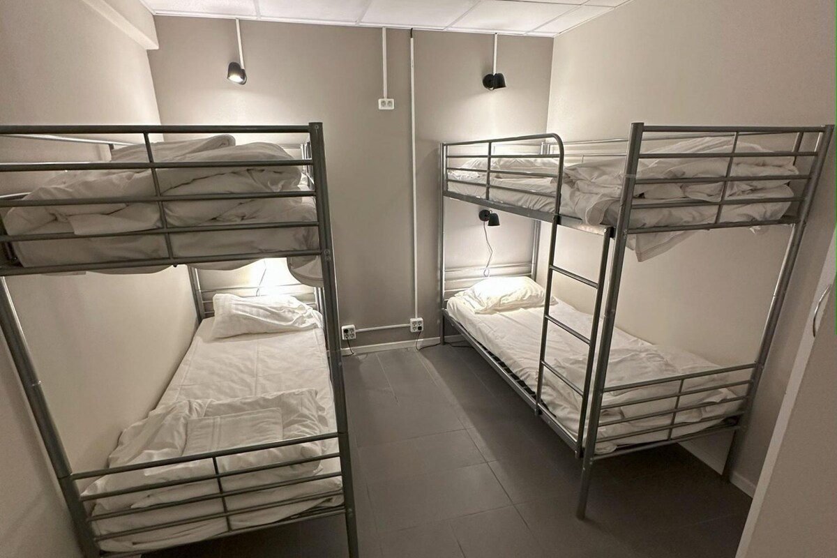 A 6-bed dormitory room with bunk beds, a shared bathroom, and no windows.