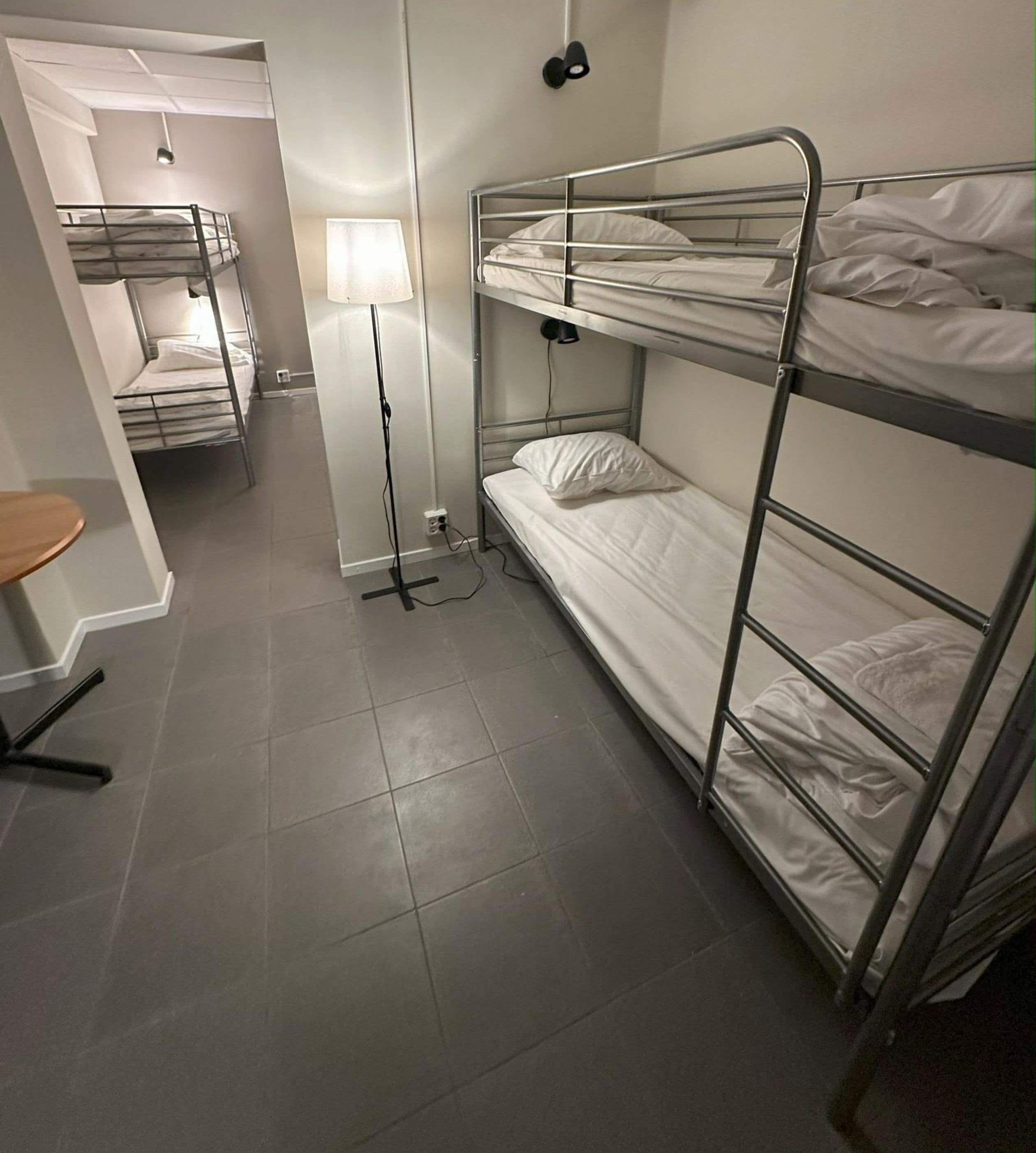 Un dormitorio con seis camas, literas, baño compartido y sin ventana.